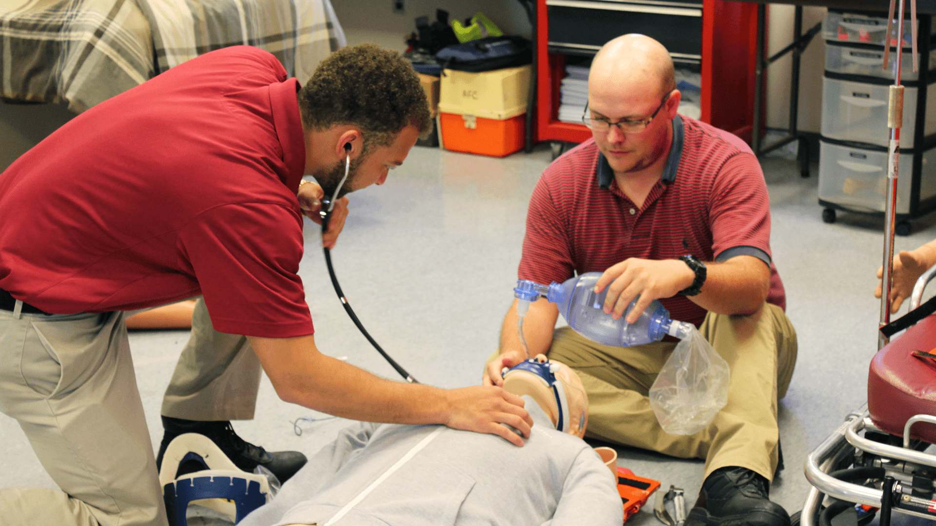 Two students practice first responder skills on a dummy.